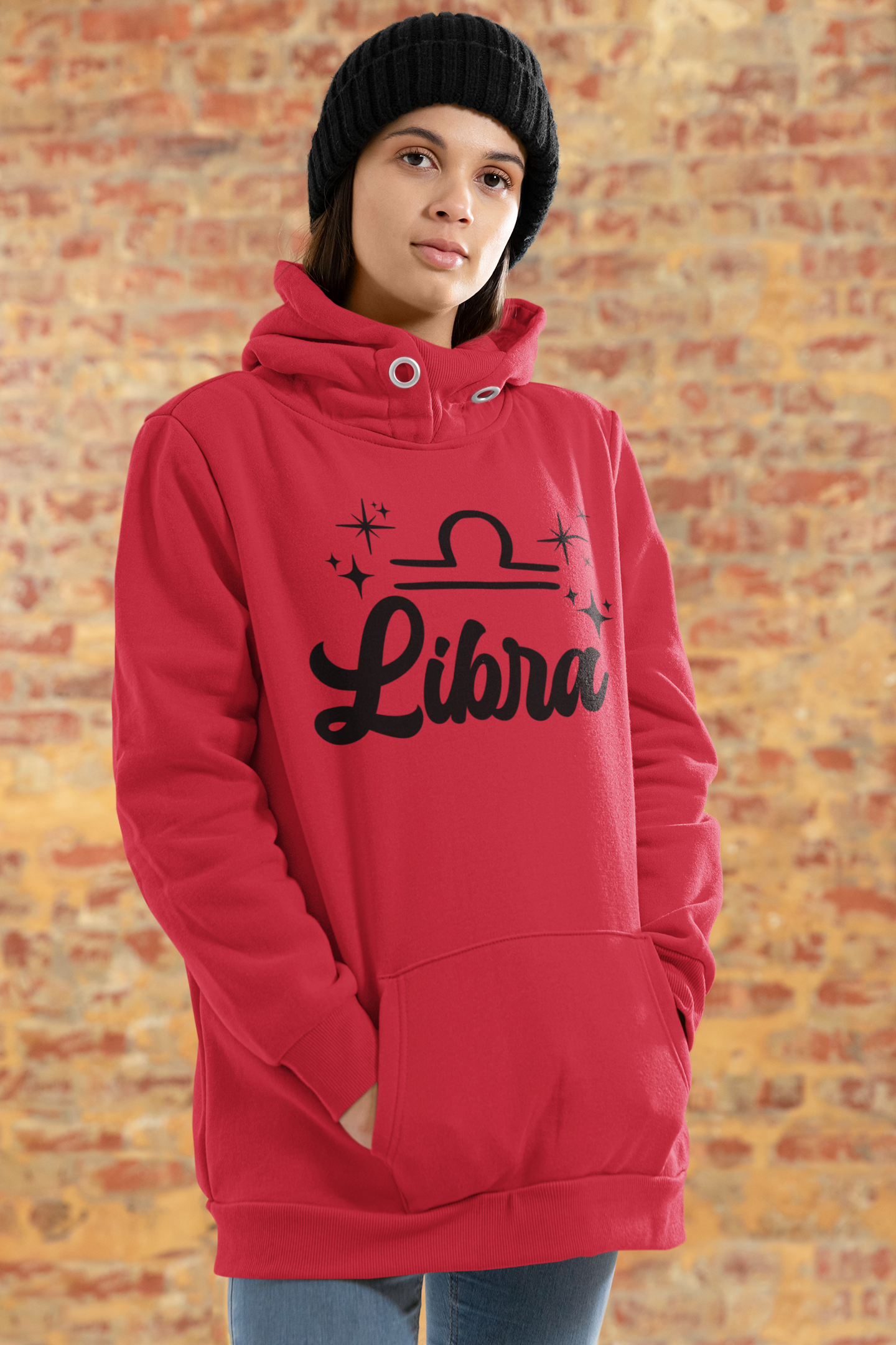 Person wearing a red hoodie with 'Libra' black text design standing in front of a brick wall.