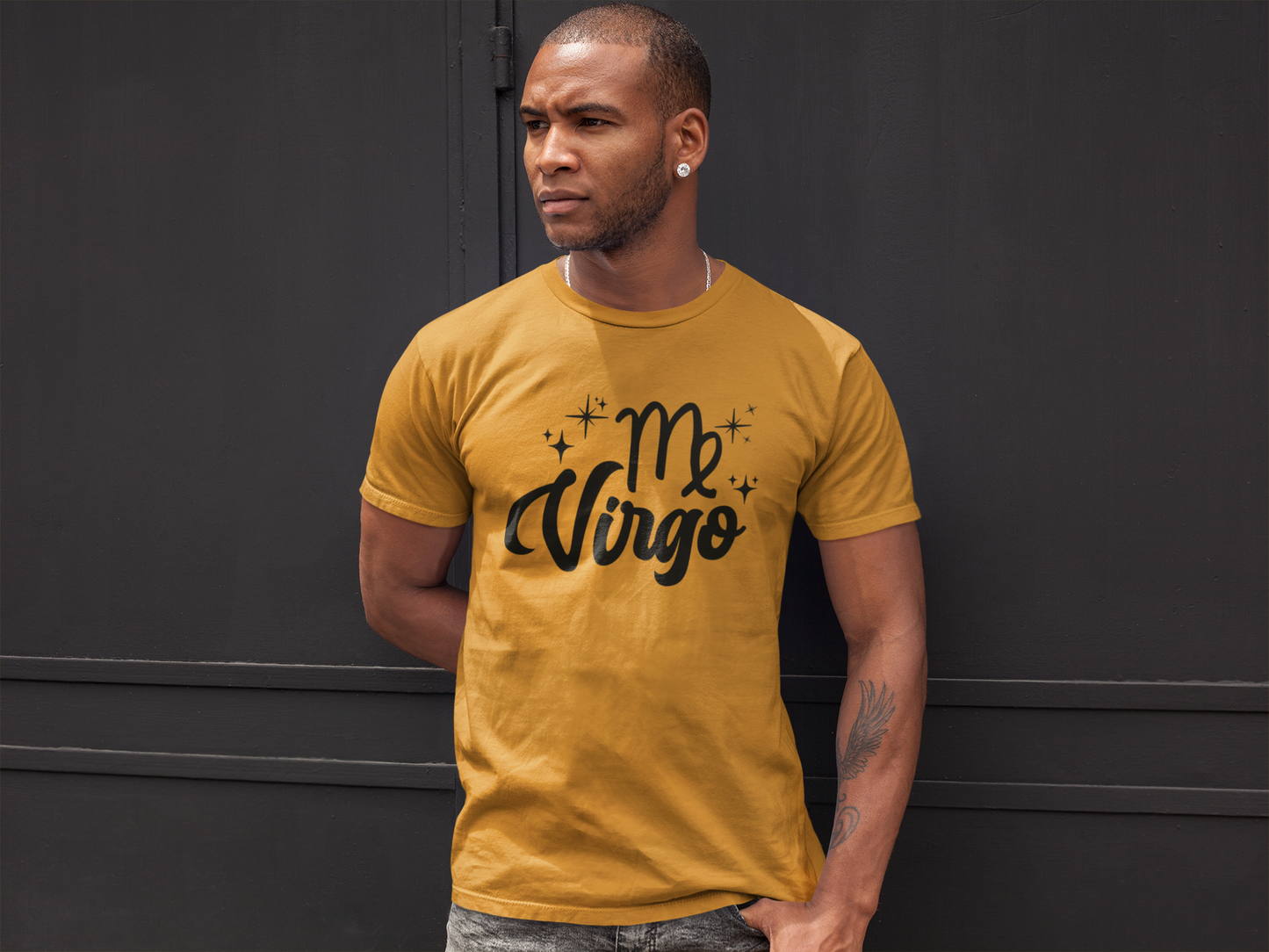 Man wearing a gold t-shirt with 'Virgo' black text against a black wall background
